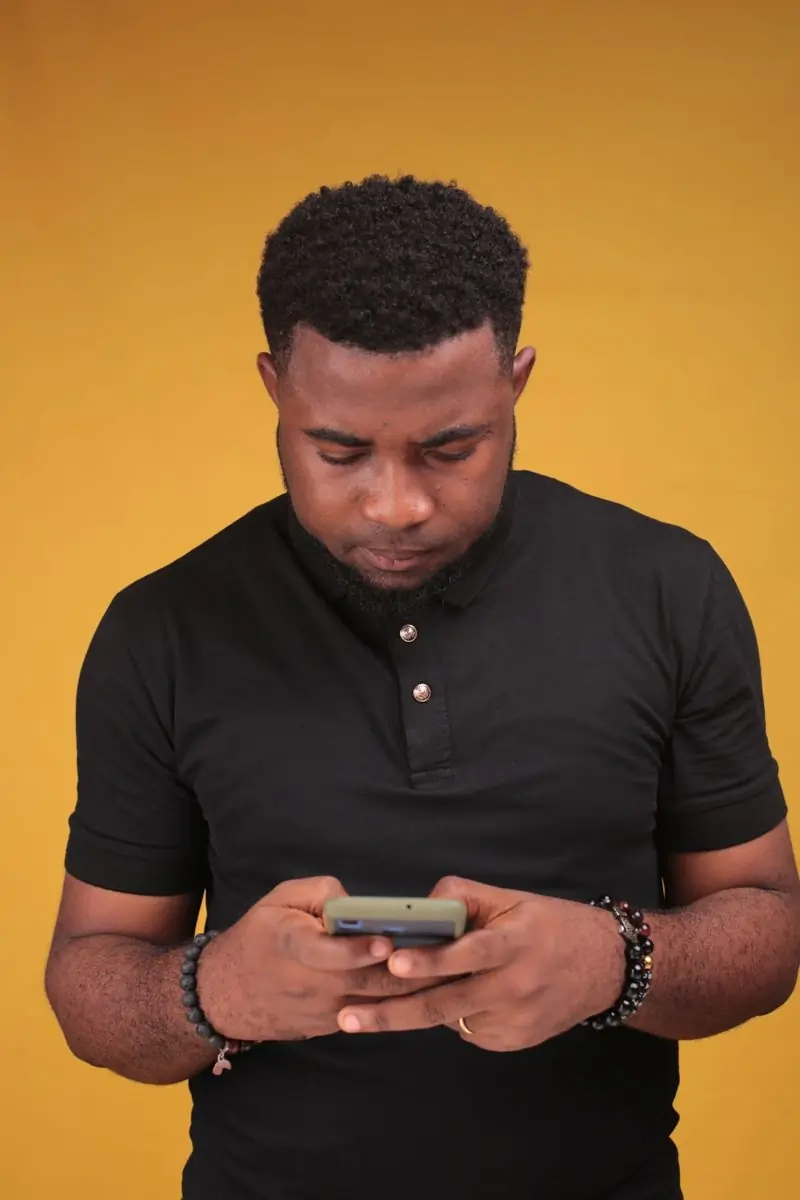 A man in a brown polo shirt photographed against a yellow ground