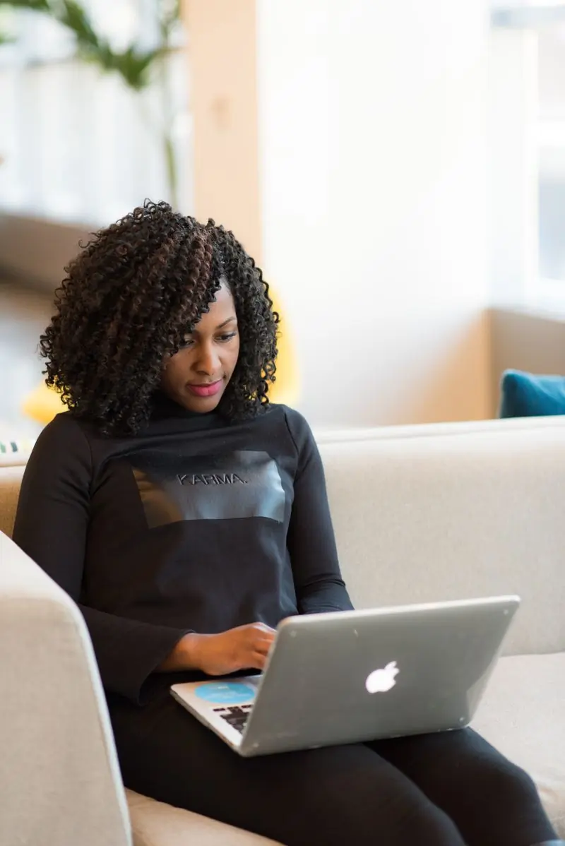A person with curly hair working at a laptop indoors