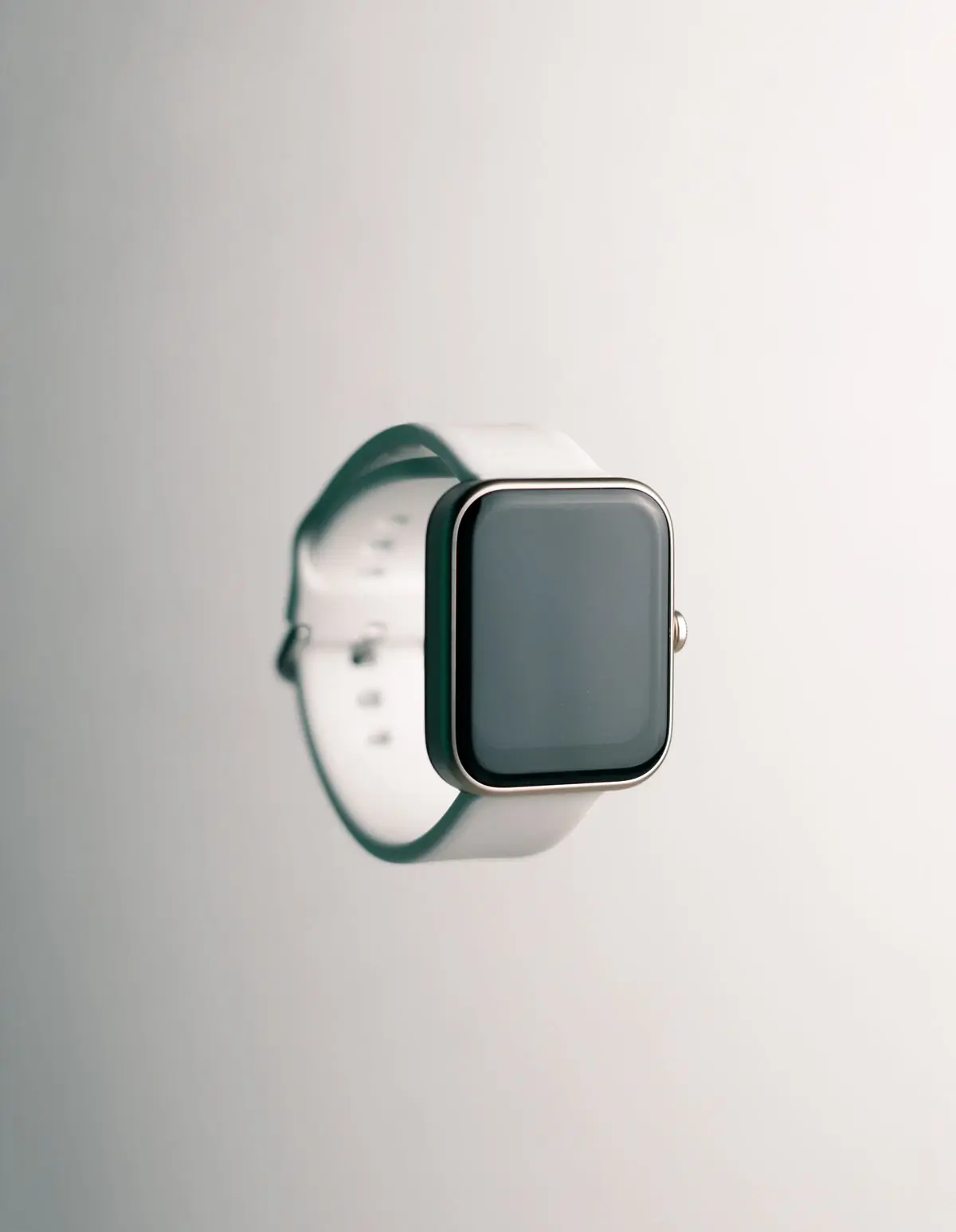 A smartwatch with a pale sport strap, close up on a soft ground