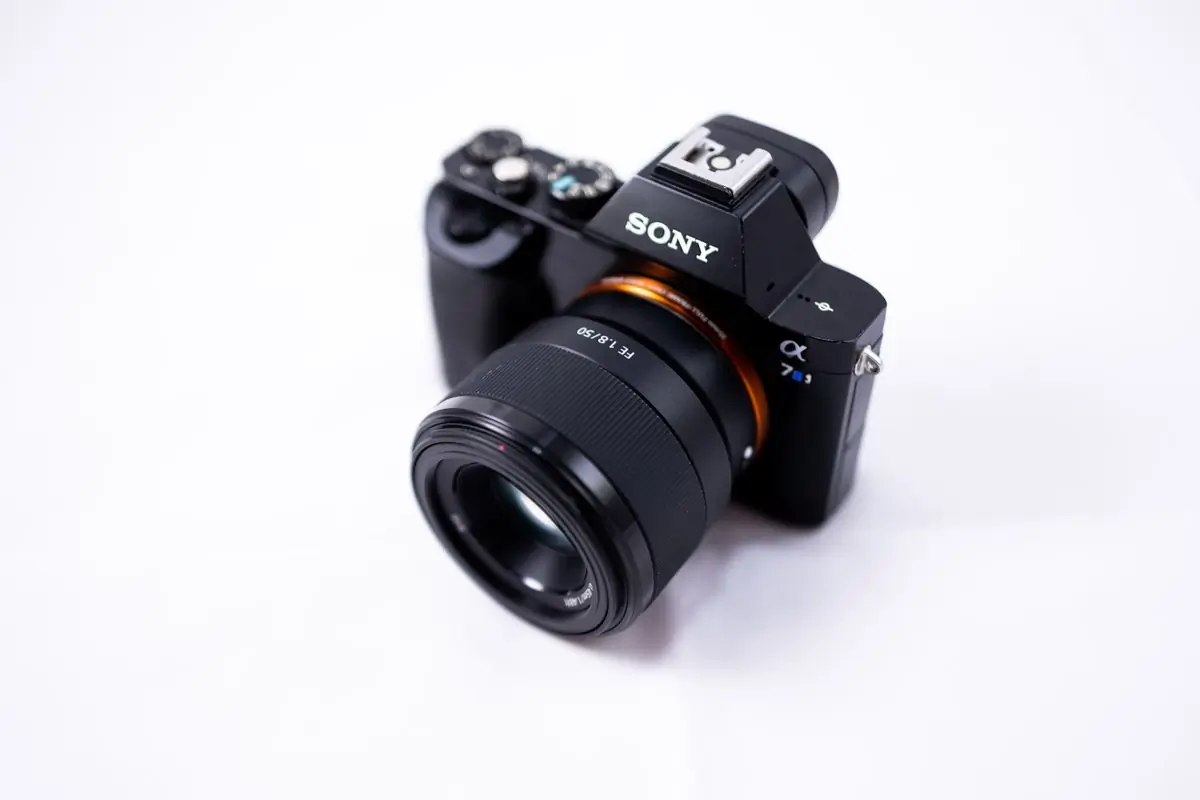 A compact mirrorless camera seen front on against white