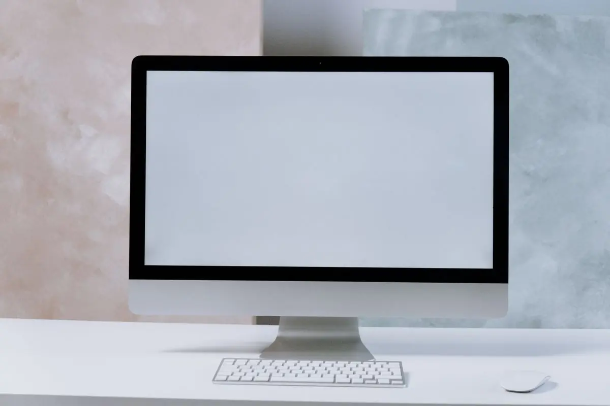 A desktop computer and its keyboard on a plain white desk
