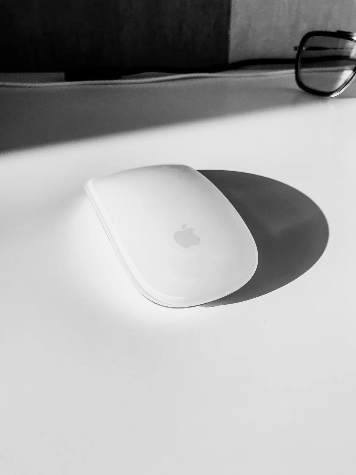 A slim white wireless mouse on a pale desk