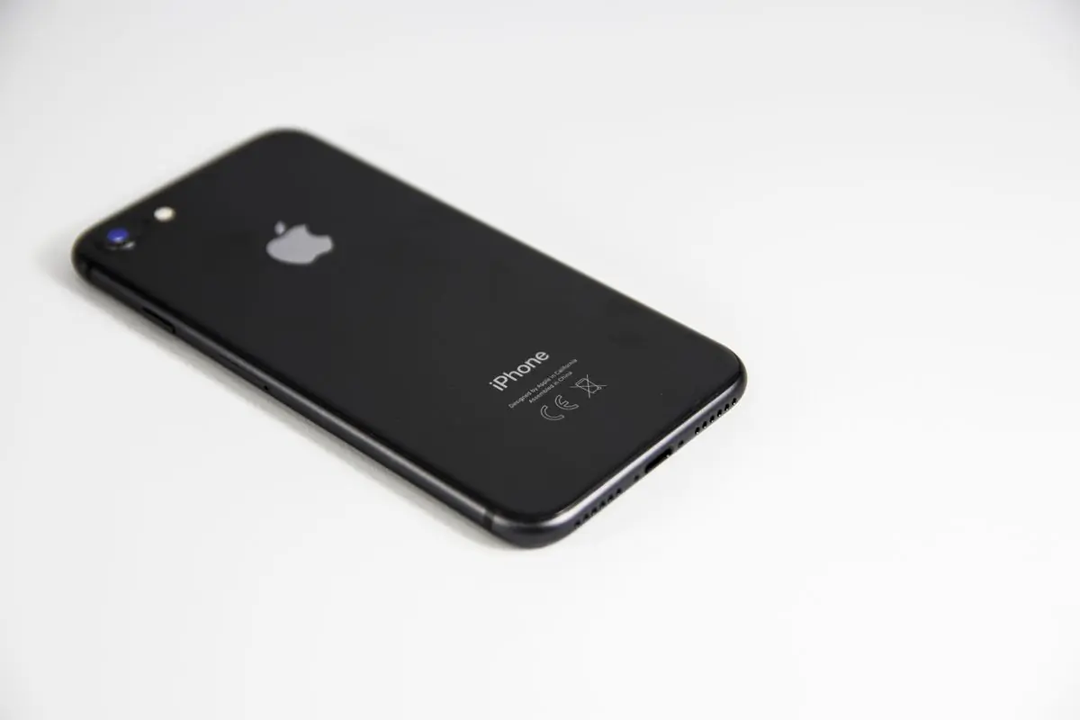 A black smartphone lying face down on a plain white surface