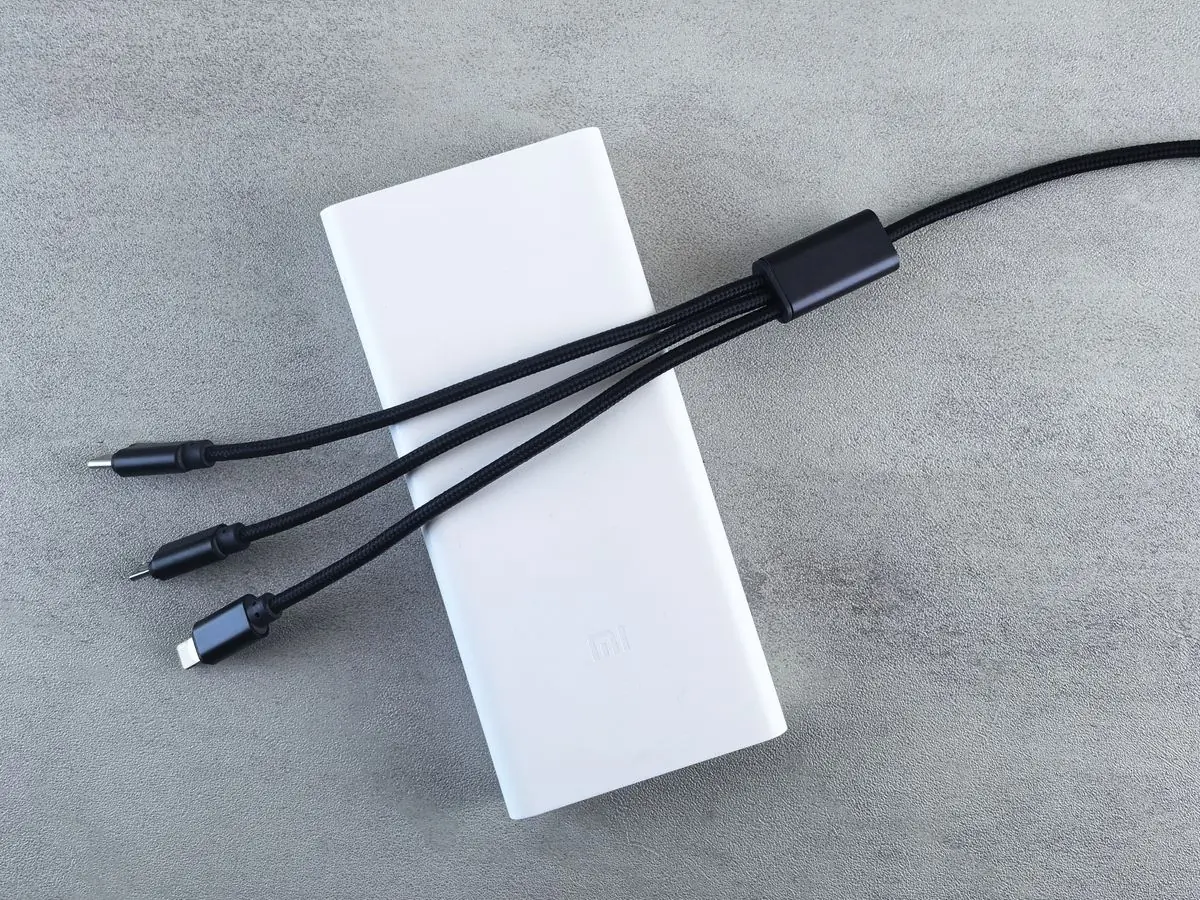 A white power bank and its multi-connector cable on pale grey