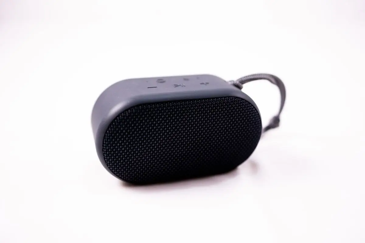 A compact fabric-covered portable speaker on white