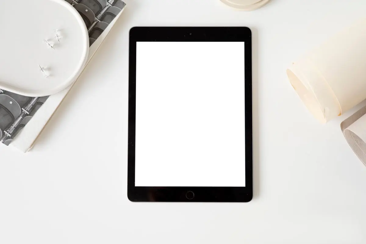 A tablet with a blank screen lying flat on a white desk