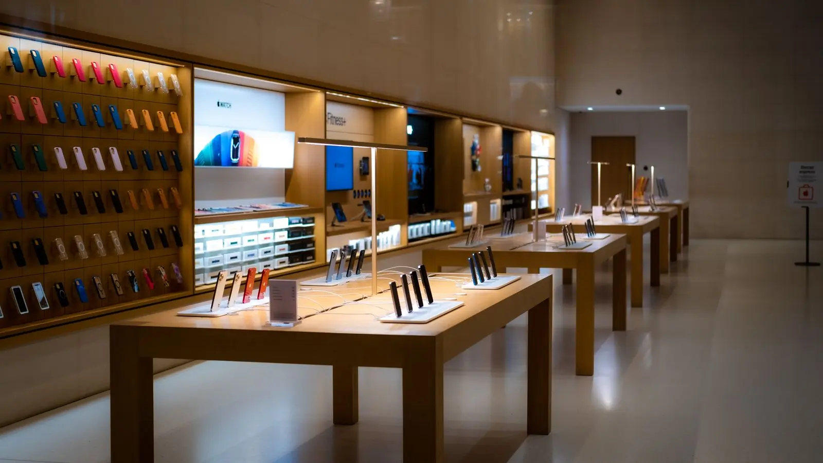 A bright electronics shop with devices laid out on pale wooden tables