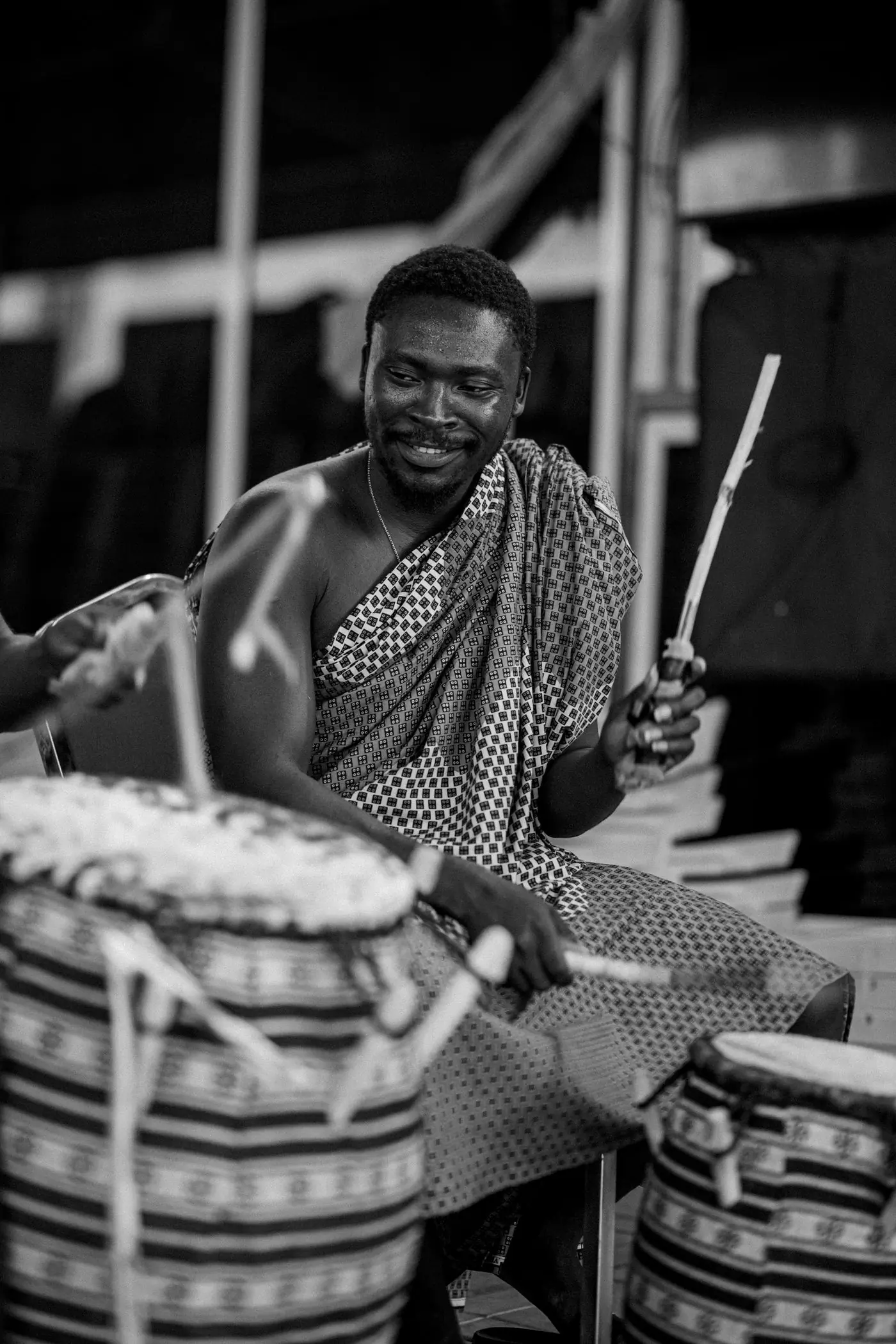 A drummer in patterned cloth smiling behind his drum