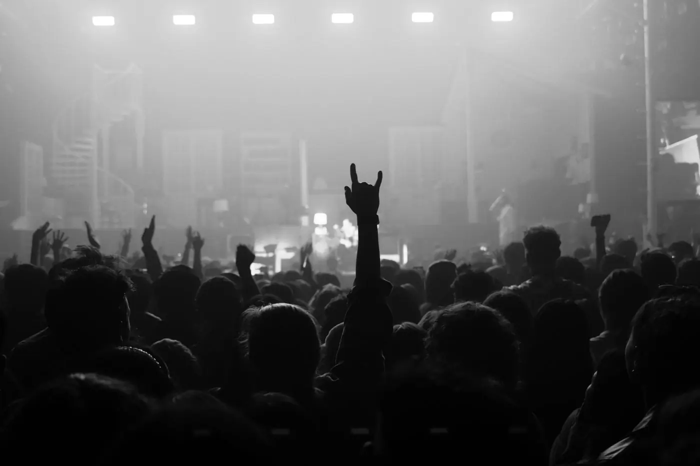 A raised hand in a crowd silhouetted against stage haze