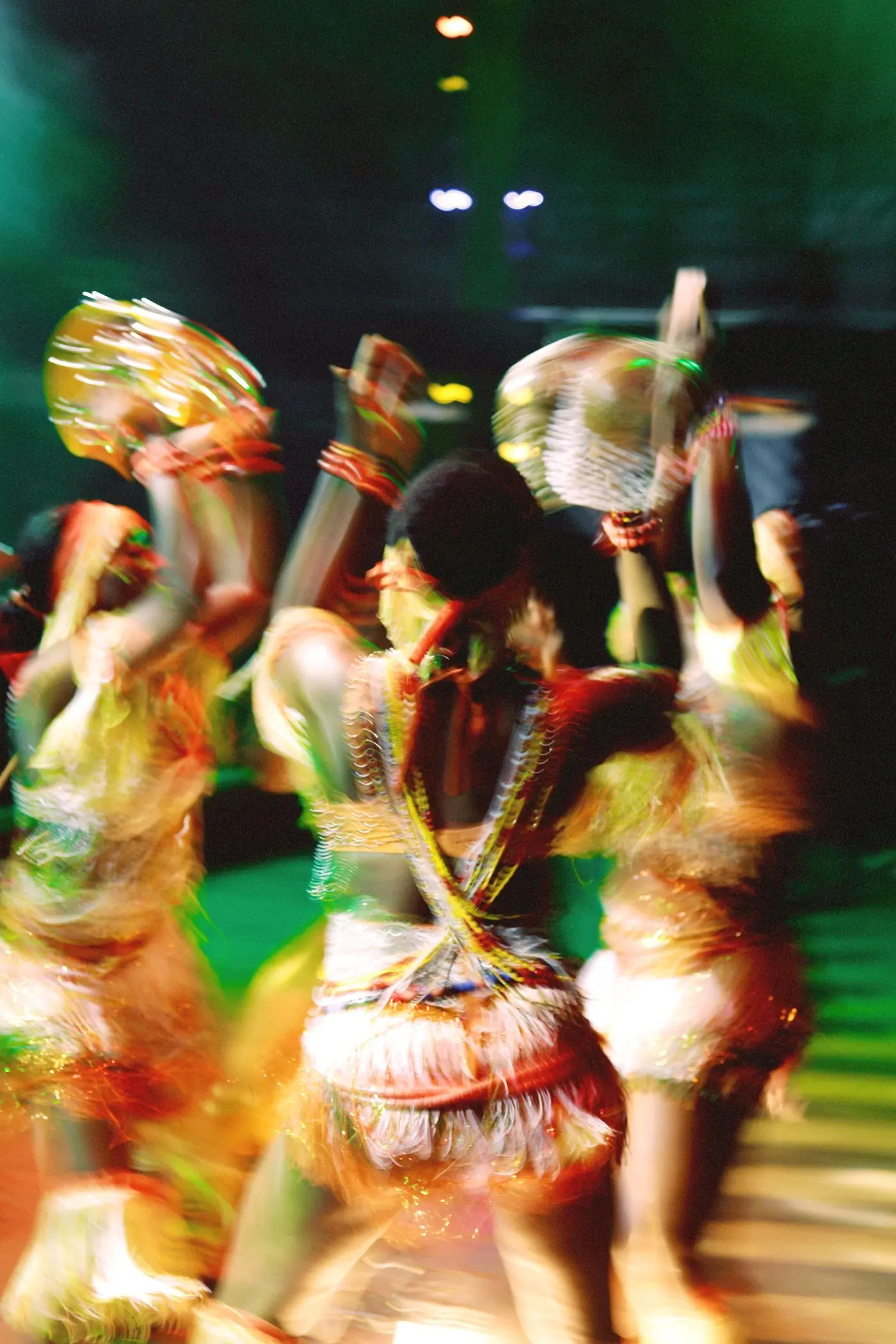 Dancers blurred by motion under green and gold stage light