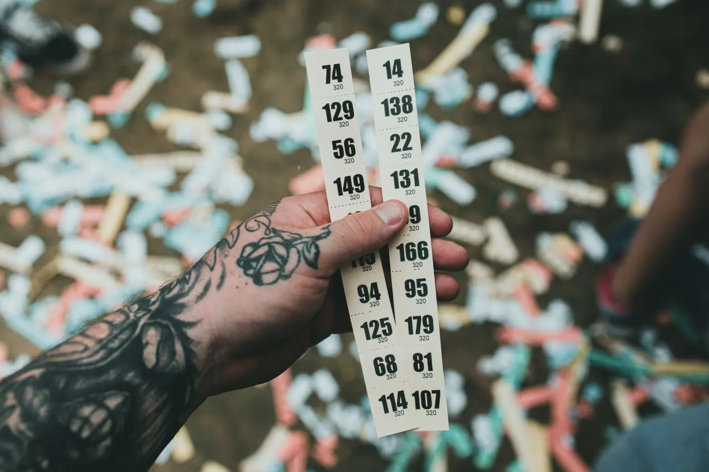 A hand holding a strip of numbered paper tickets over confetti