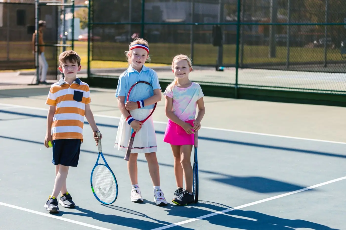 Three campers with rackets on the camp tennis court