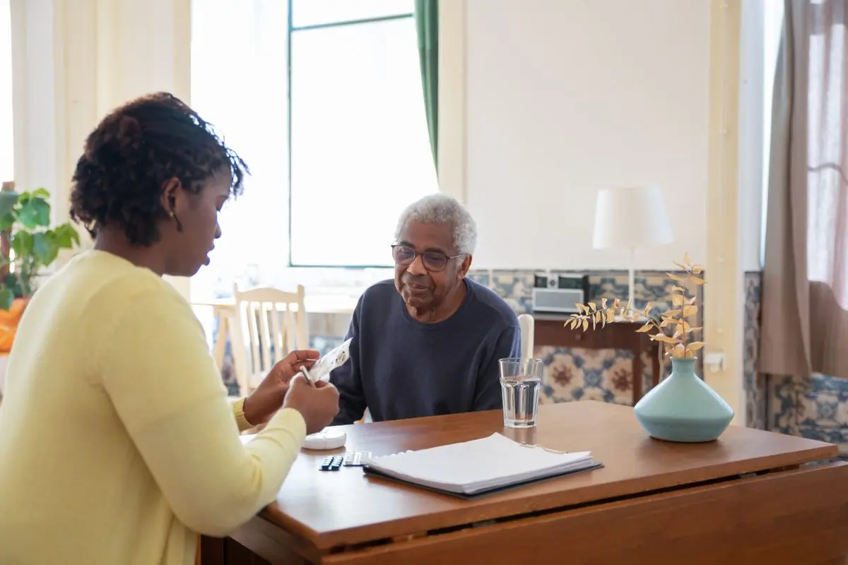 A carer going through a patient's medicines with him at home