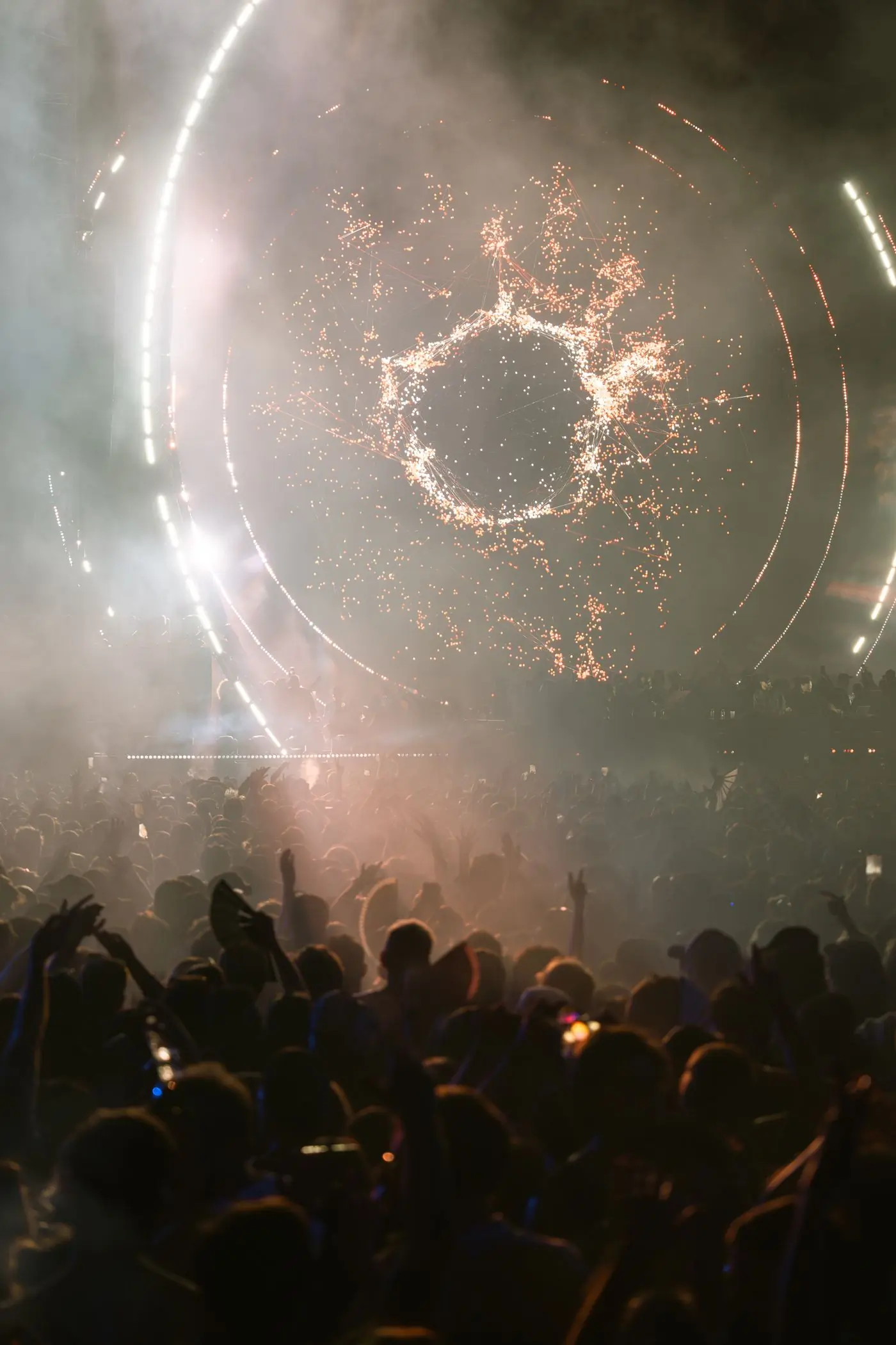 A mirror ball scattering light over a crowd through smoke