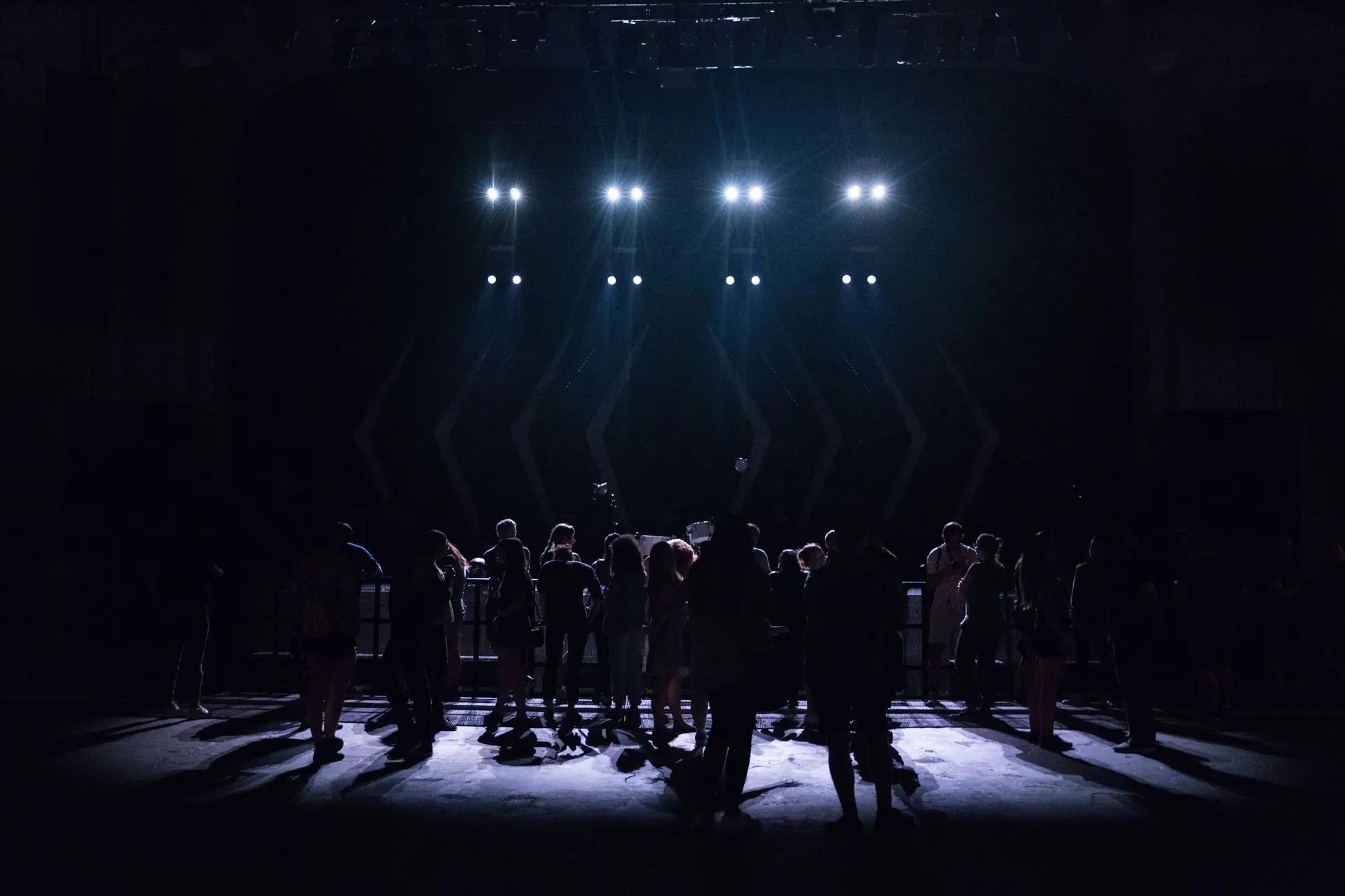 A crowd in silhouette in front of a bank of stage lights at a night festival