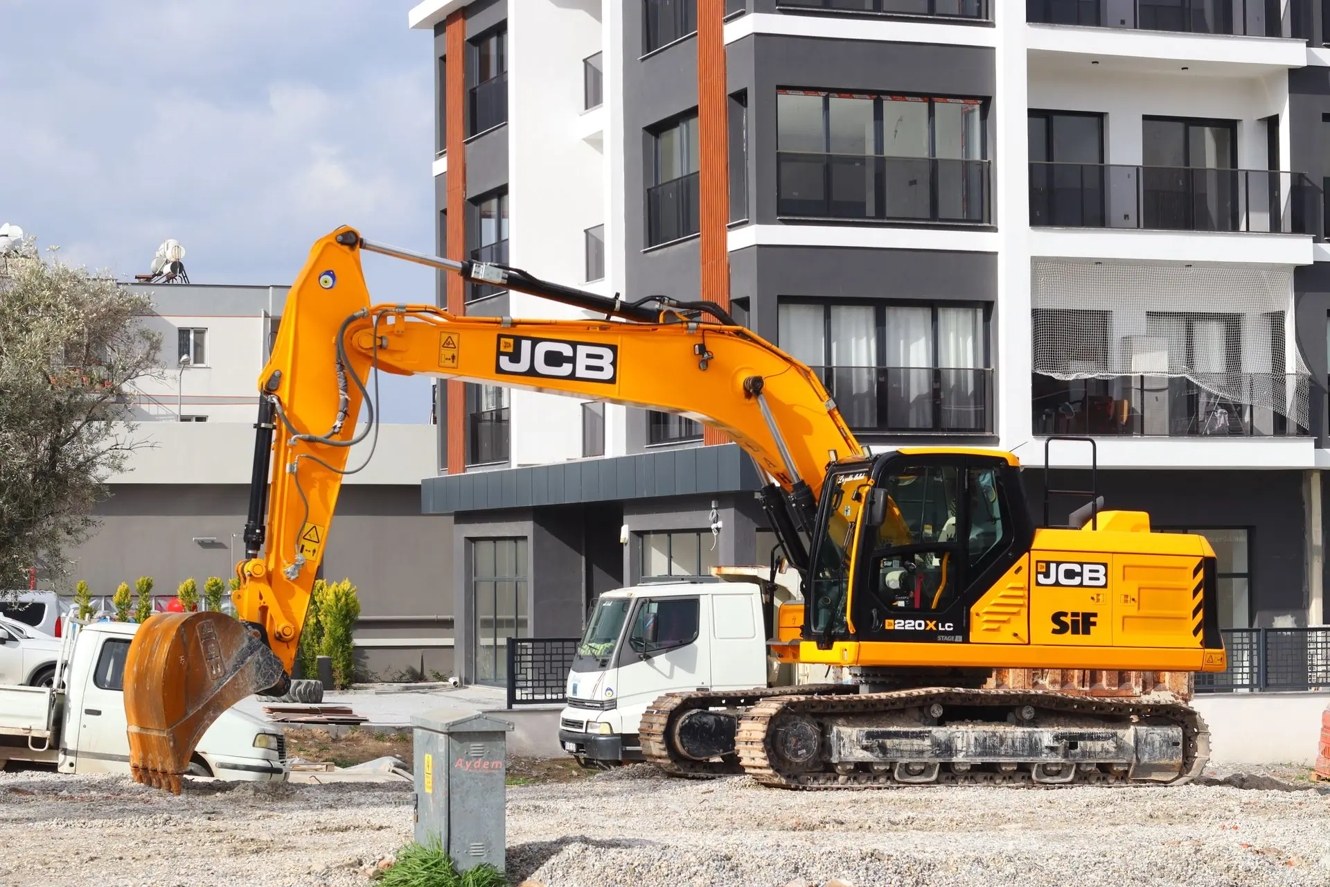 An excavator working in front of a newly finished apartment block