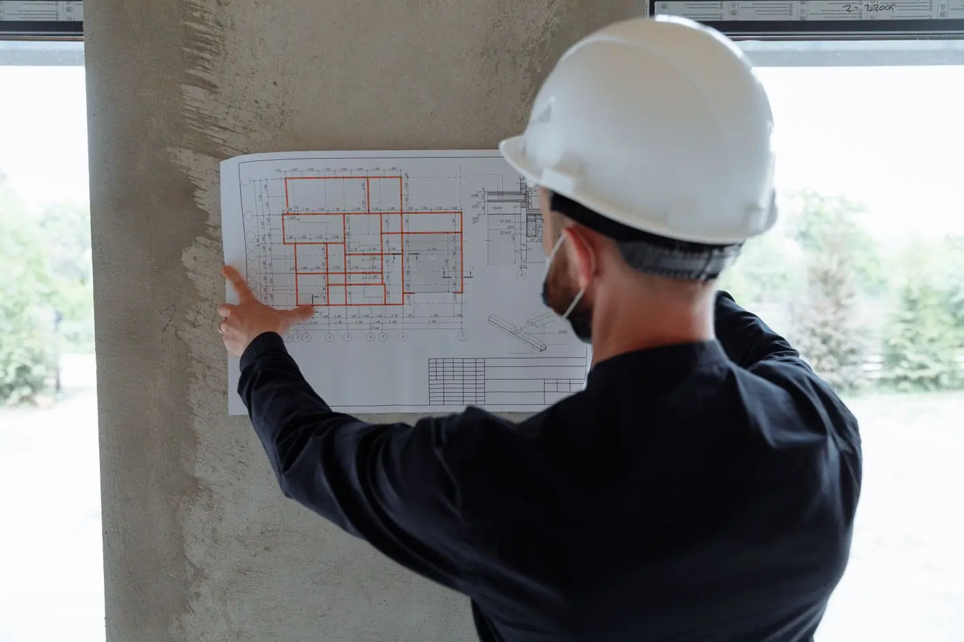 An engineer holding a floor plan against a wall