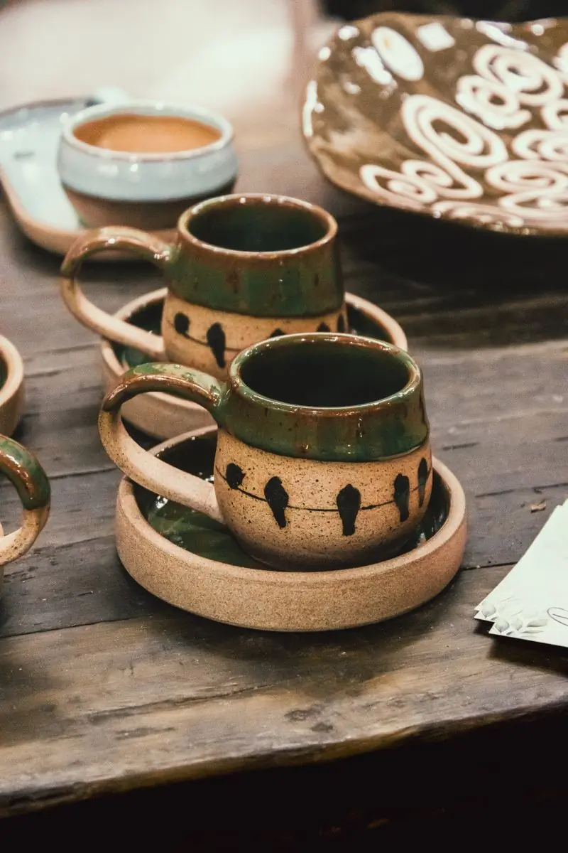 Two speckled stoneware mugs stacked on their saucers