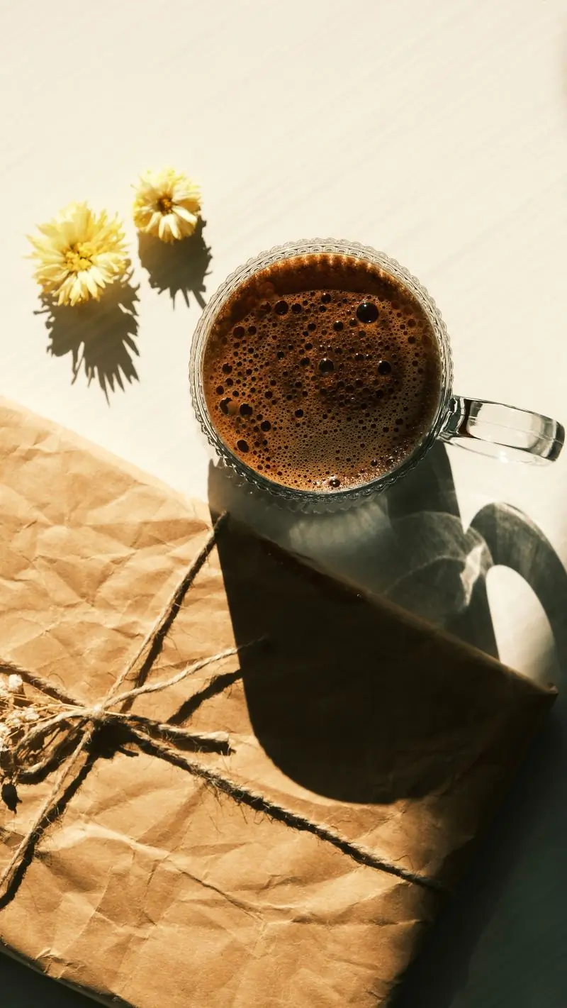 A mug of coffee resting on a kraft parcel tied with jute twine