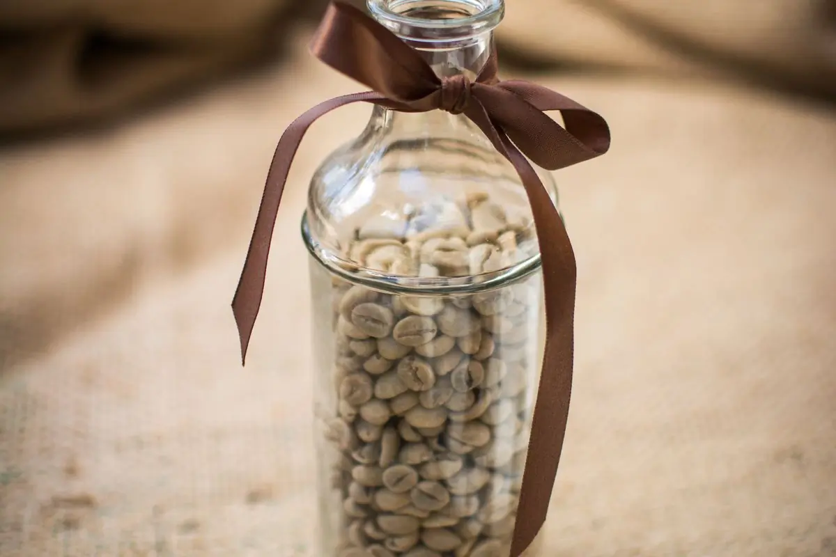 A bottle of green beans tied at the neck with ribbon, standing on a coffee sack