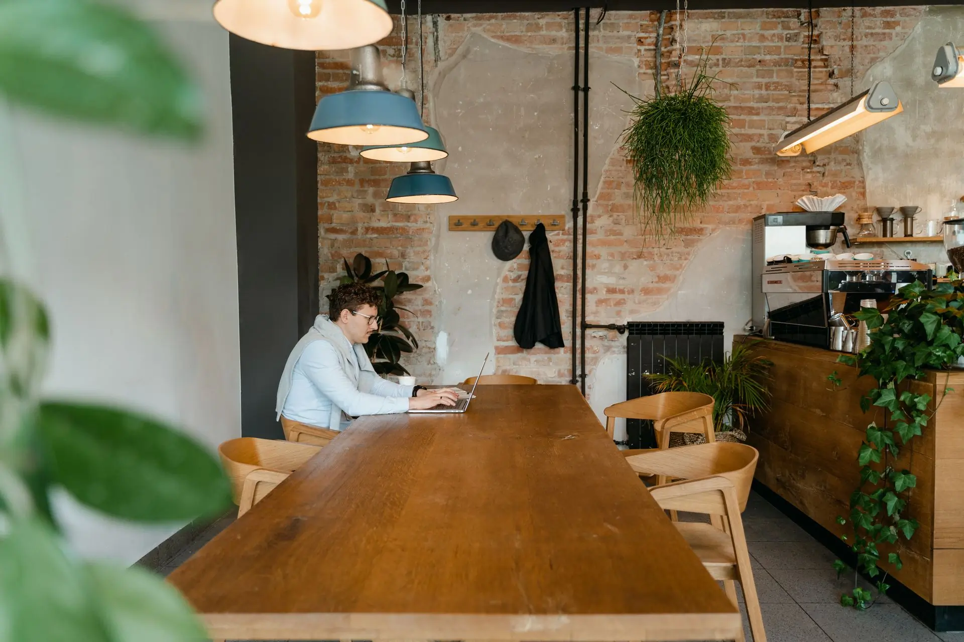 The long communal table running down the brick room, with the counter set out at the far end