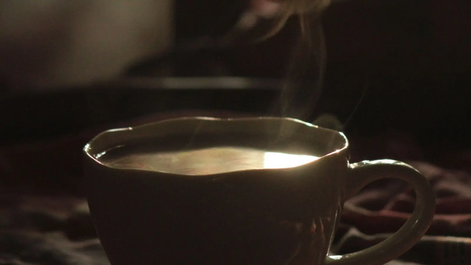 Steam curling off a full cup on a table in the last of the afternoon light