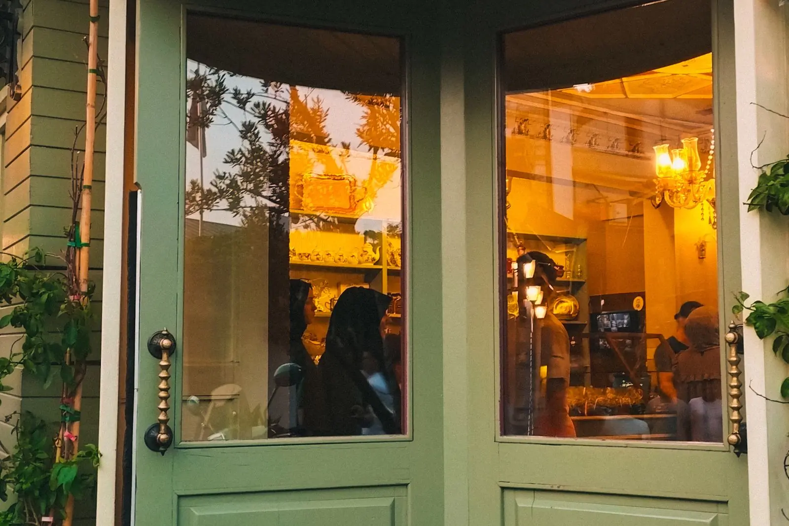 The sage green doors of the Osu shop, with the room behind them lit and full