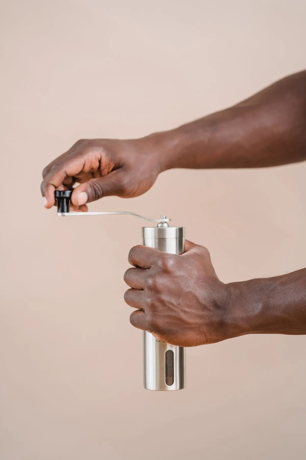 Hands turning the crank of the steel hand grinder