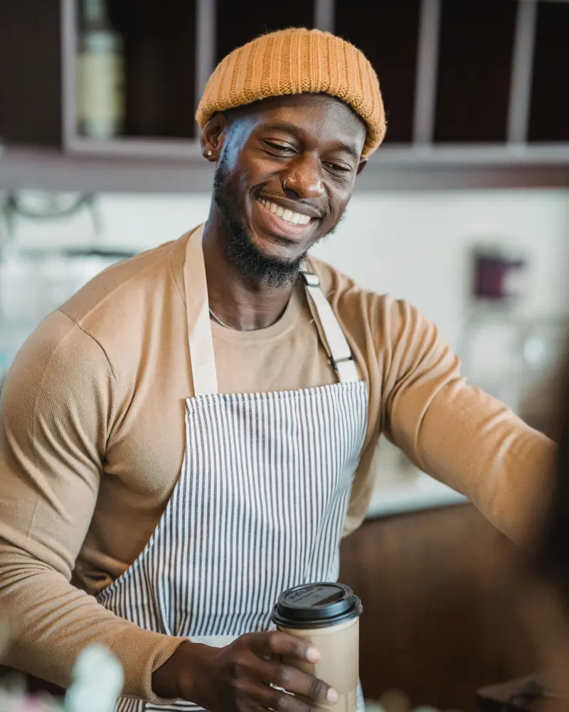 Kofi behind the counter with a fresh cup in his hand