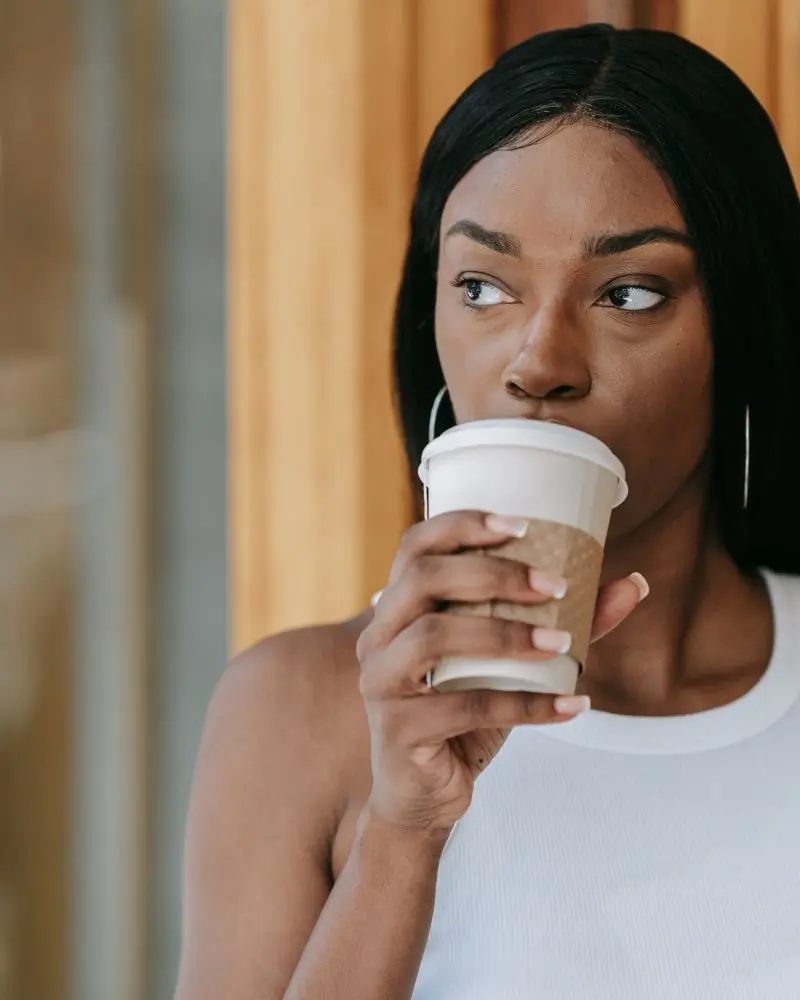 A customer pausing over a takeaway cup in the morning sun