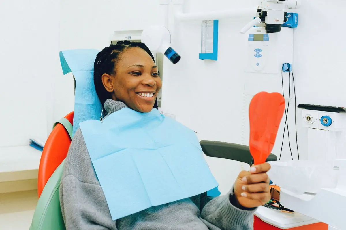 A patient looking at her new smile in a hand mirror