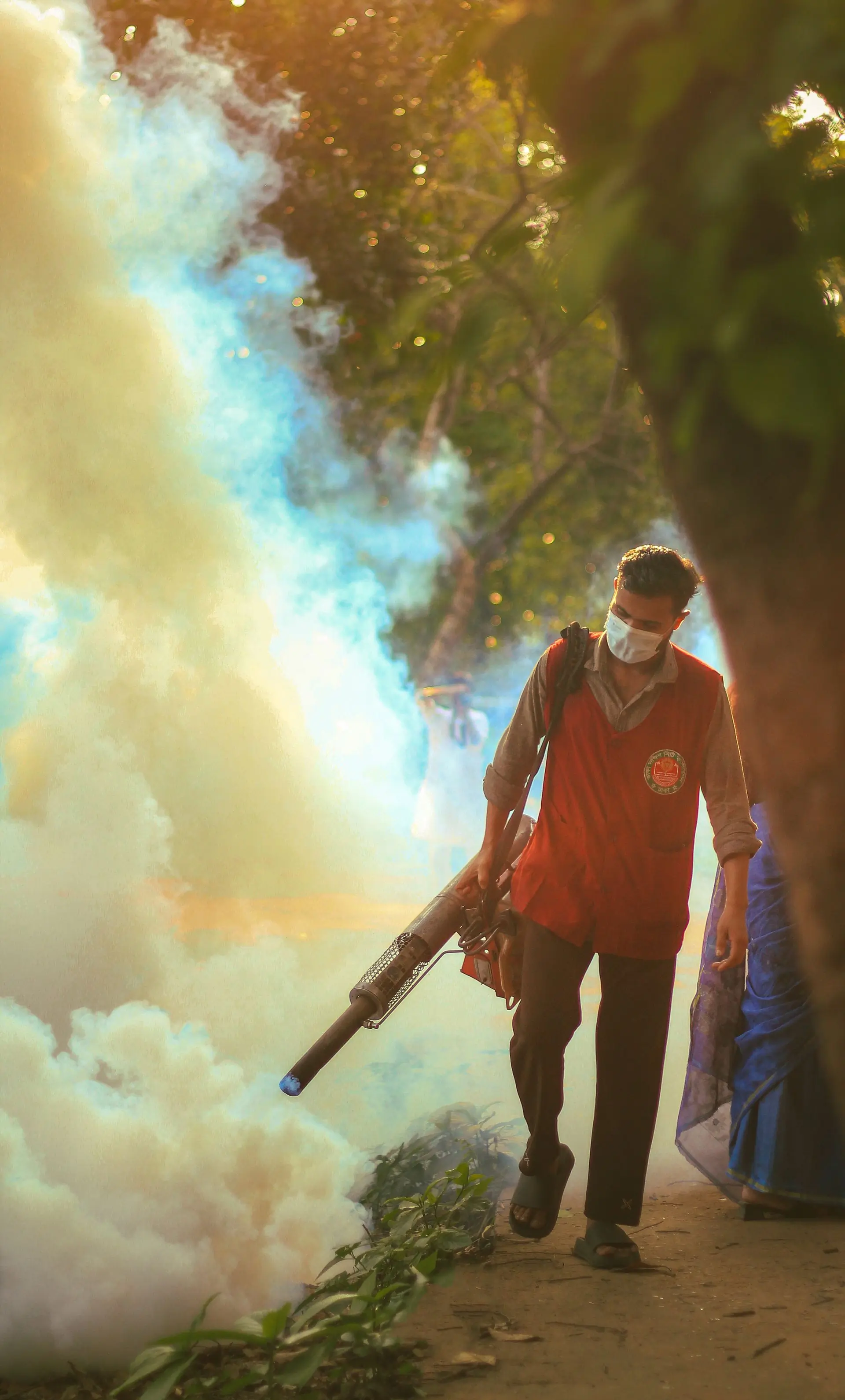 A technician fogging a public park at golden hour
