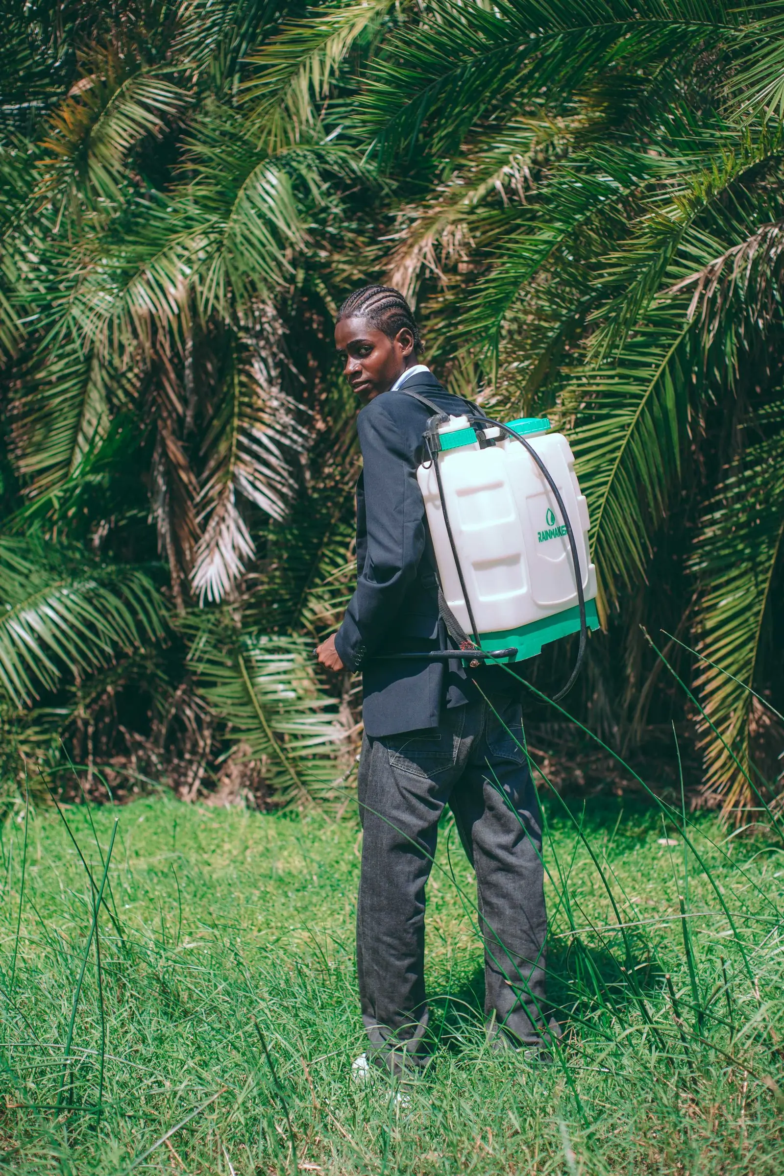 A technician carrying a sprayer through a planted compound