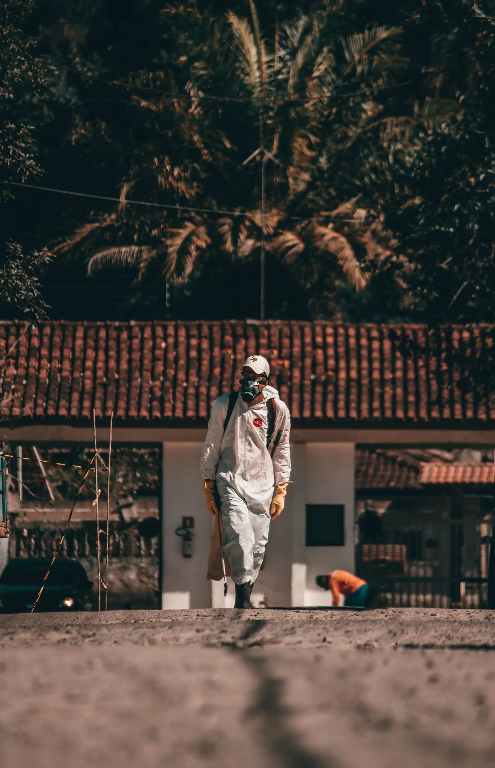 A technician in full protective kit walking a compound at first light