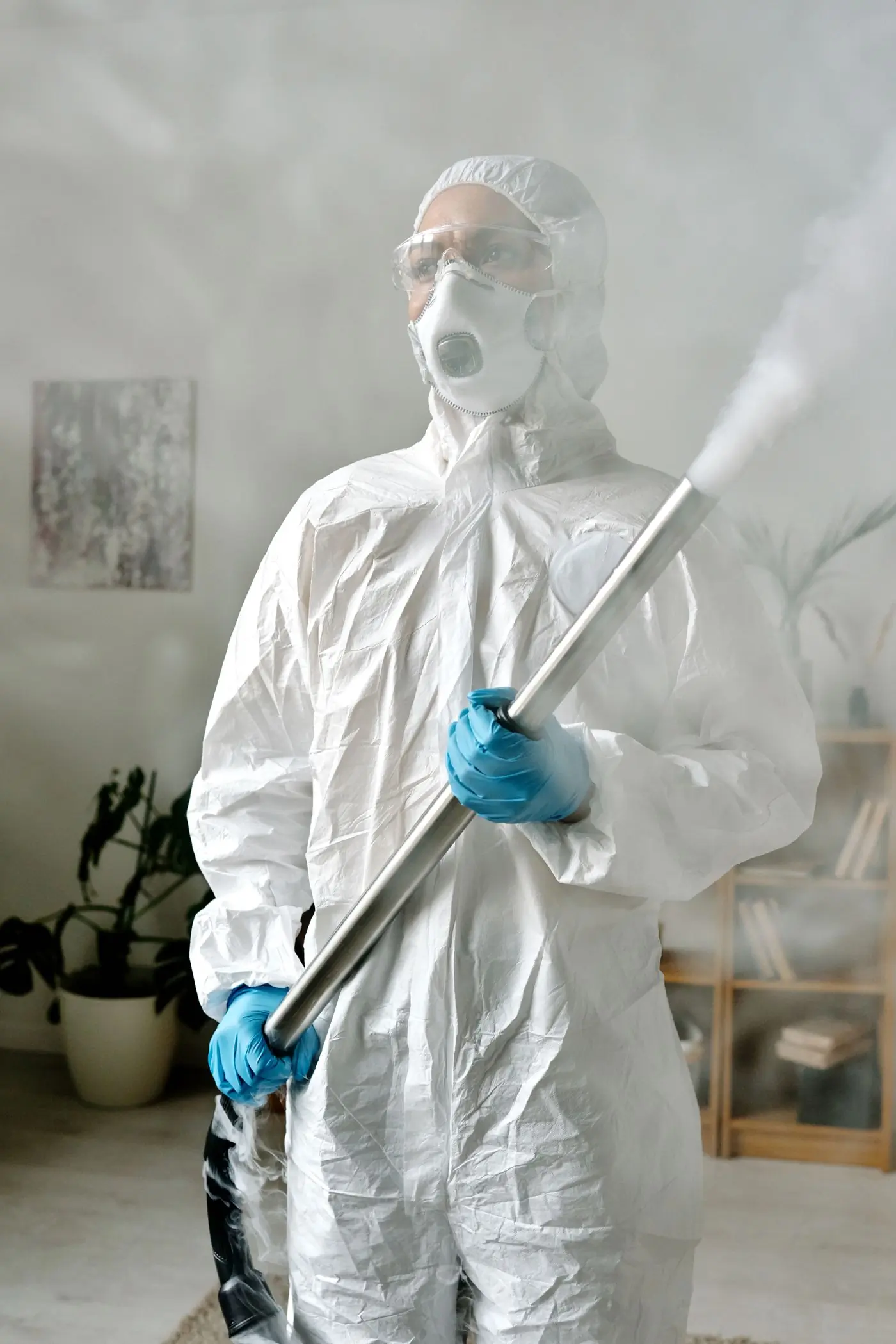 A technician in a protective suit treating a room with a hand sprayer