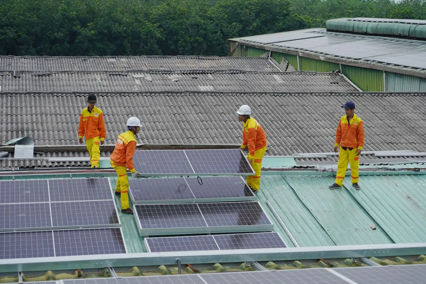 A crew of four setting panels across the long roof of an industrial building