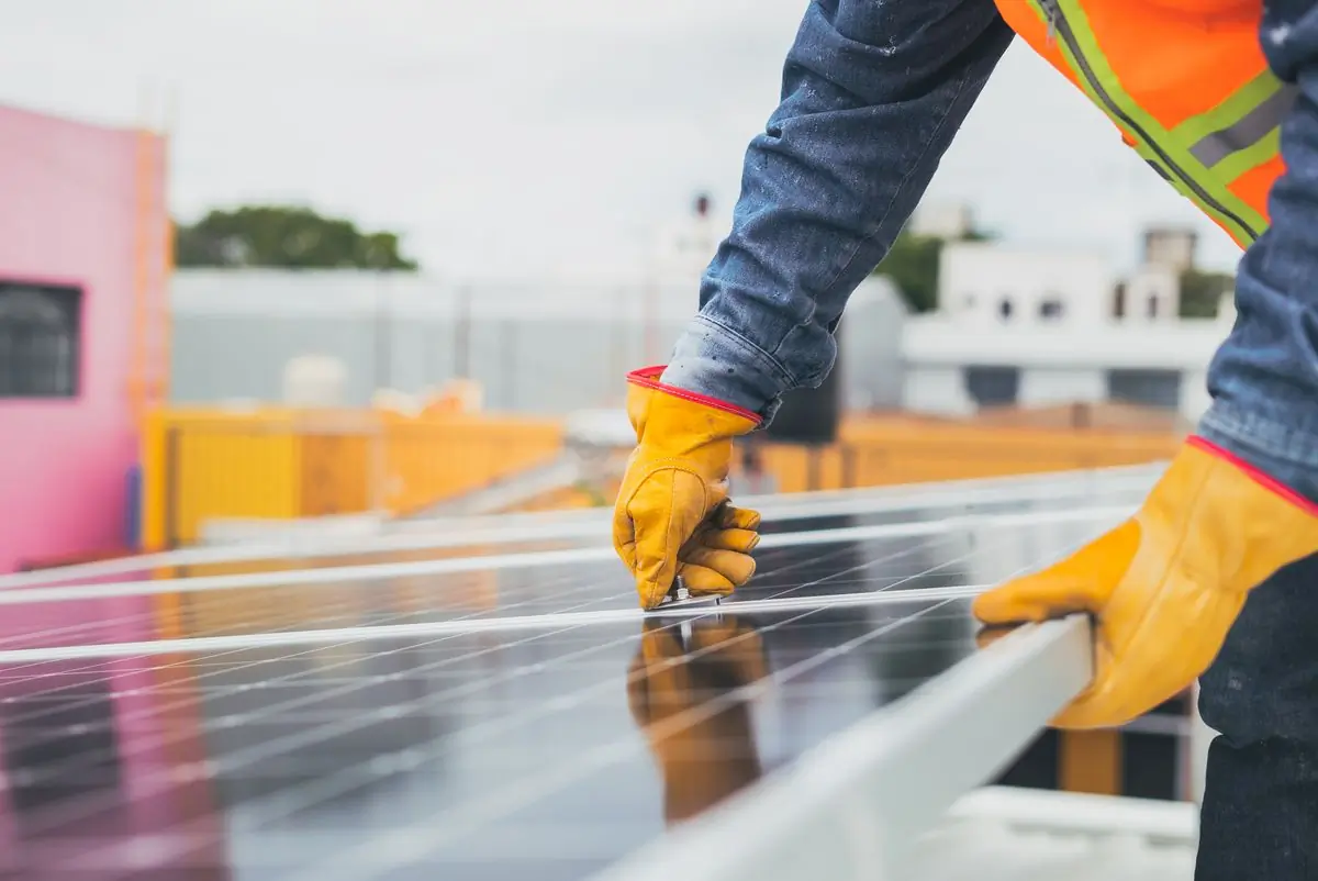A gloved technician working along the frame of a panel during a service visit