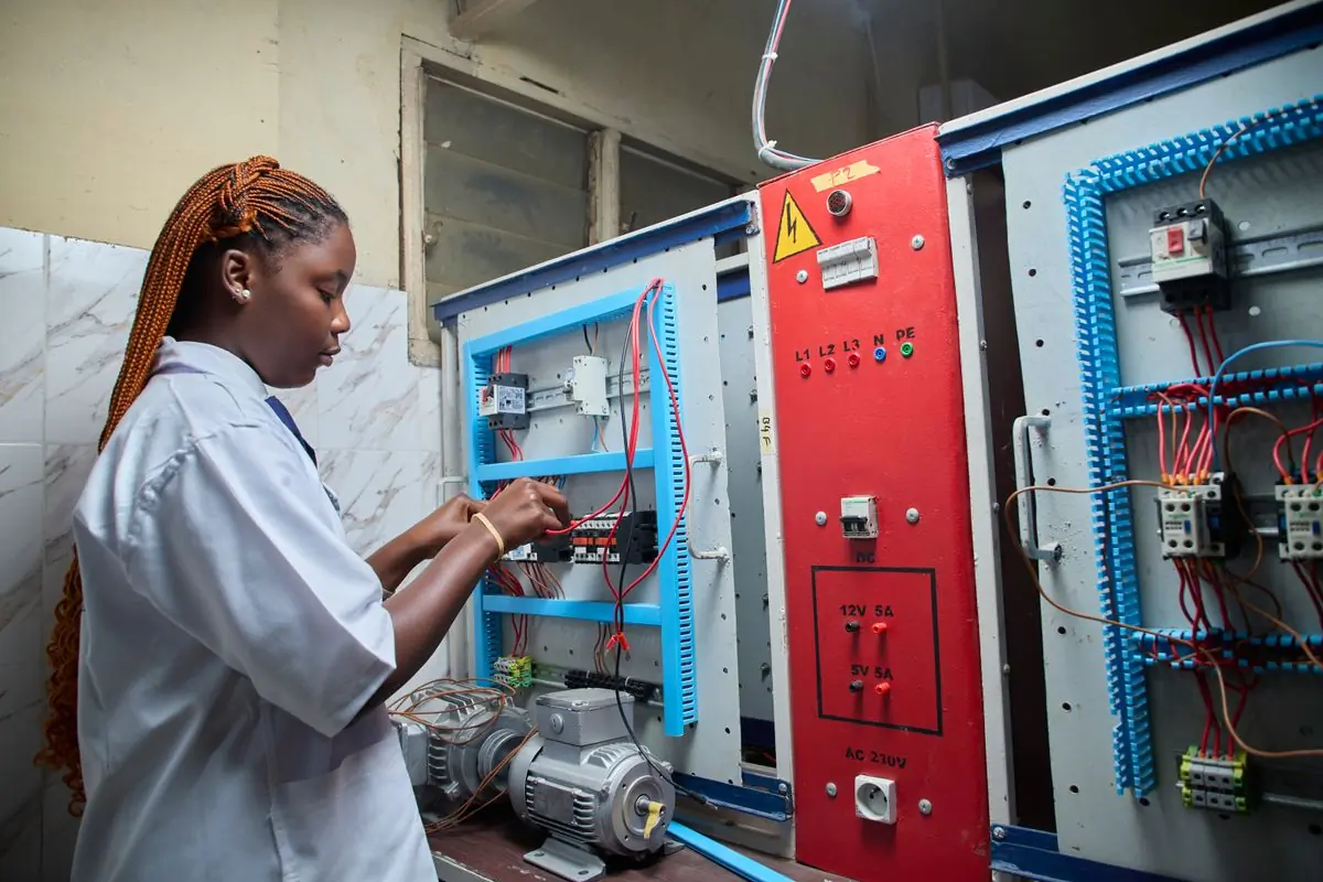 A technician working inside an open electrical control panel