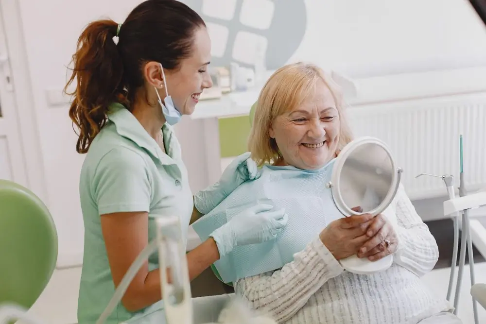 An older patient seeing her new smile in the mirror