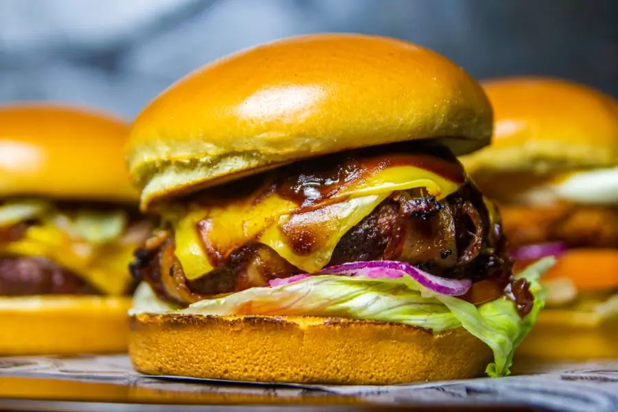 A beef burger topped with cheddar and onions