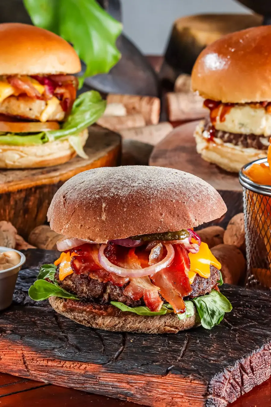 A tall double burger with bacon and cheddar on a wooden board