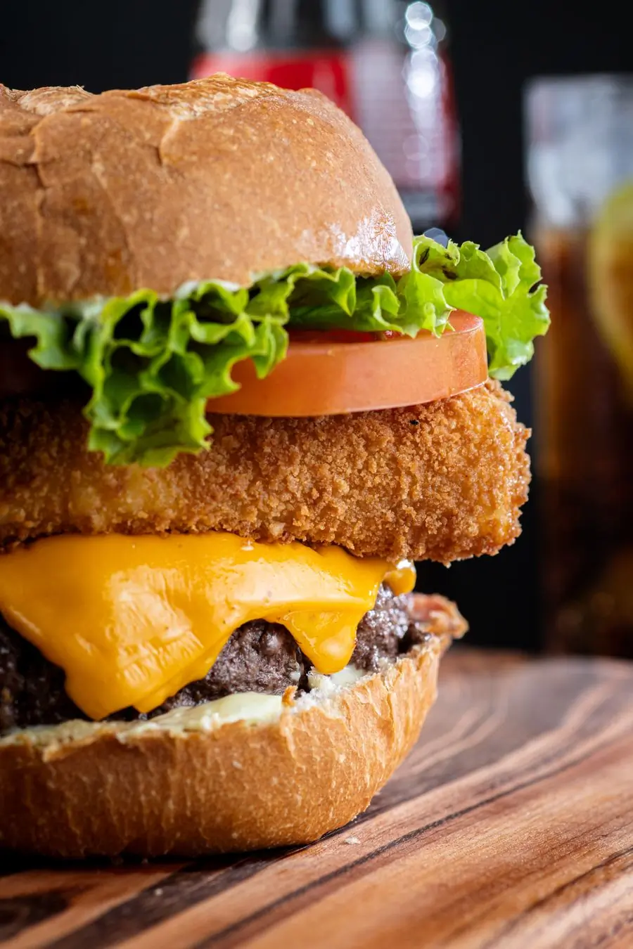 A tasty burger with cheese, lettuce and tomato on a board