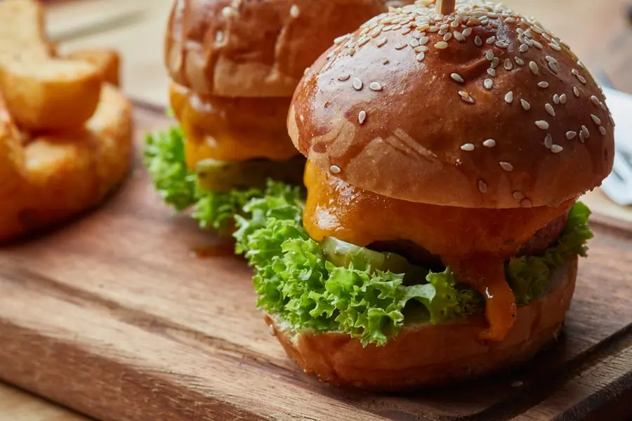 A cheeseburger with fresh lettuce and tomato on a board