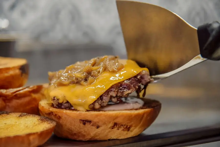 A cook laying a patty onto a bun