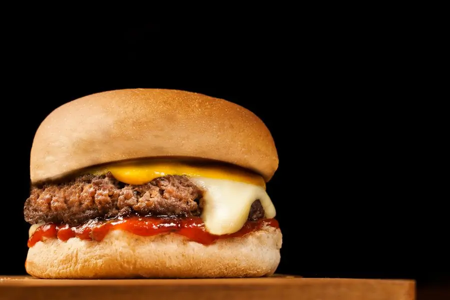 A cheeseburger with melted cheese on a bun