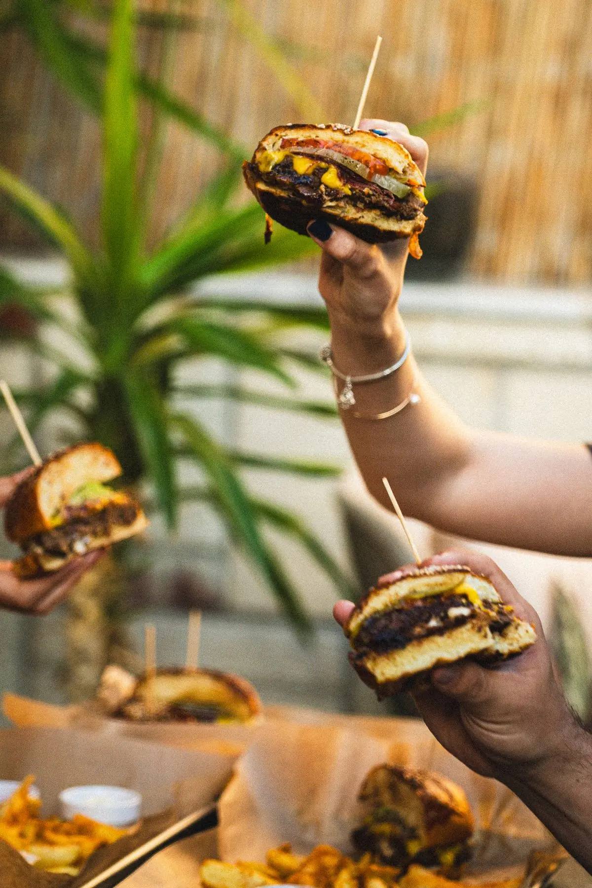 Guests raising burgers at an outdoor gathering