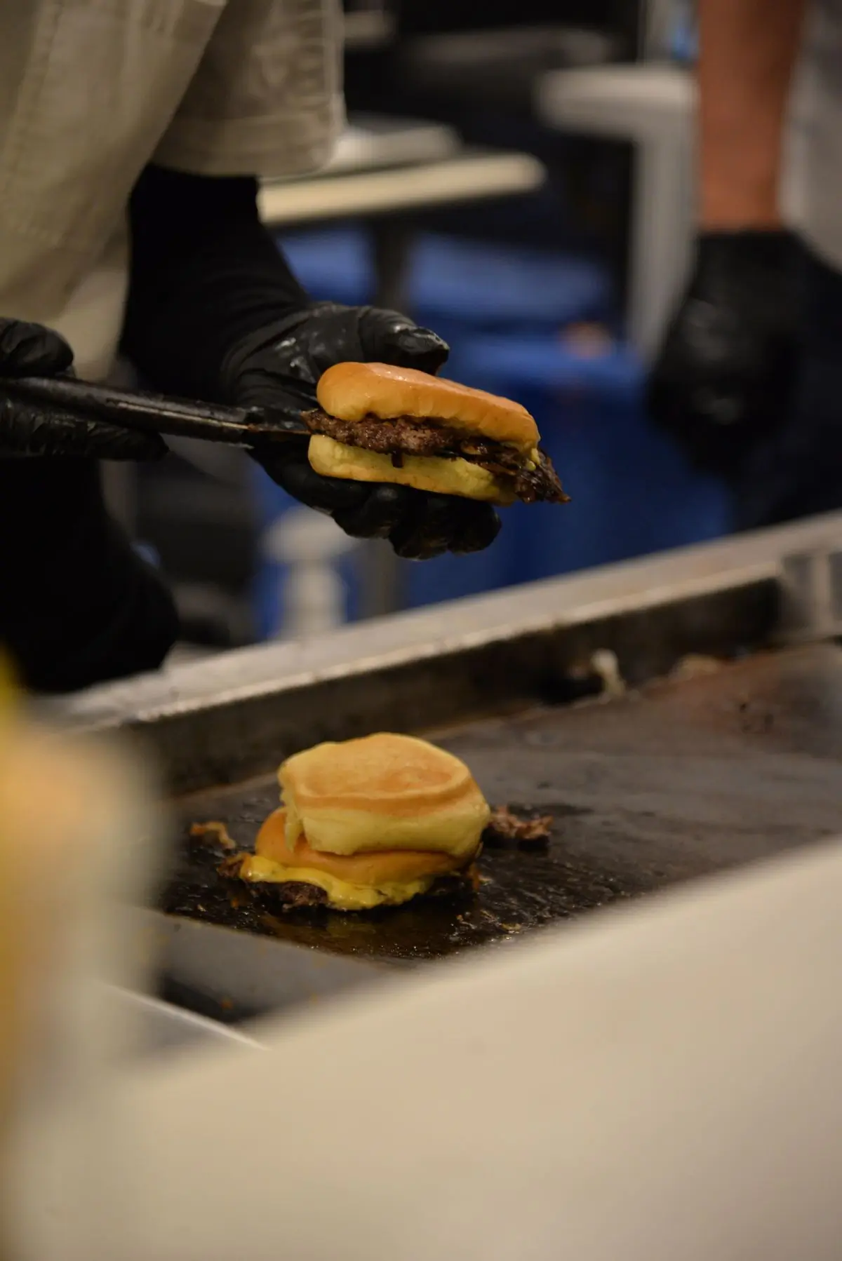 A cook flipping burger patties on the grill