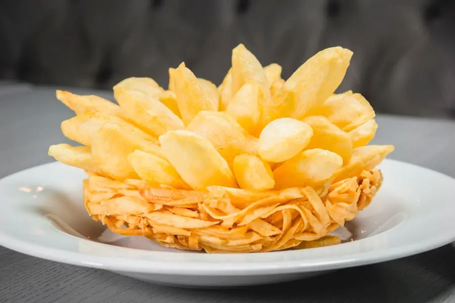 Golden hand-cut fries piled on a plate