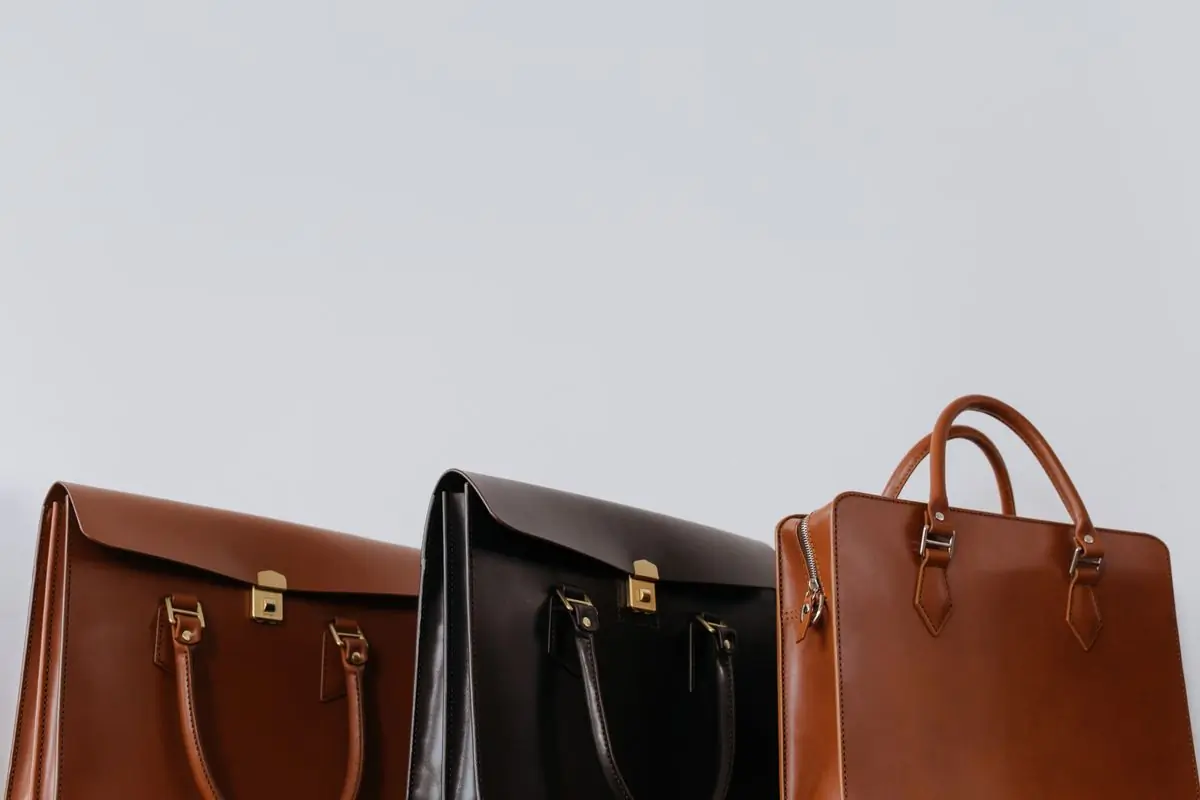 Three leather cases in chestnut, black and tan standing in a row against pale grey
