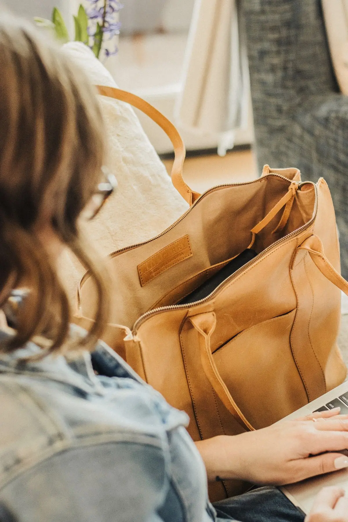 The open interior of a tan leather tote showing its lining and stitched pockets